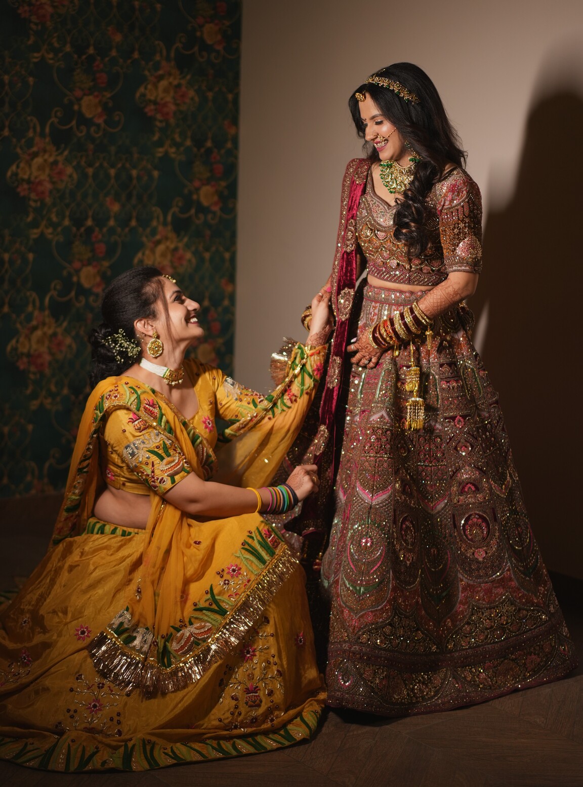 Bride smiling as her bhabhi fixes her lehenga at a Jaipur wedding